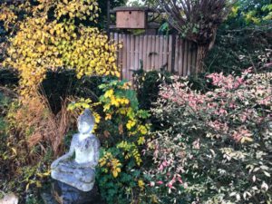 Boeddhabeeld in tuin vol herfstkleuren