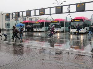 Busstation Nijmegen met reizigers in de regen