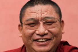 Een close up van een wijd grijnzende Chung Tsang Rimpoche.