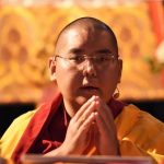 Een close up van Kyabje Yongdzin Ling Rinpoche met gevouwen handen.